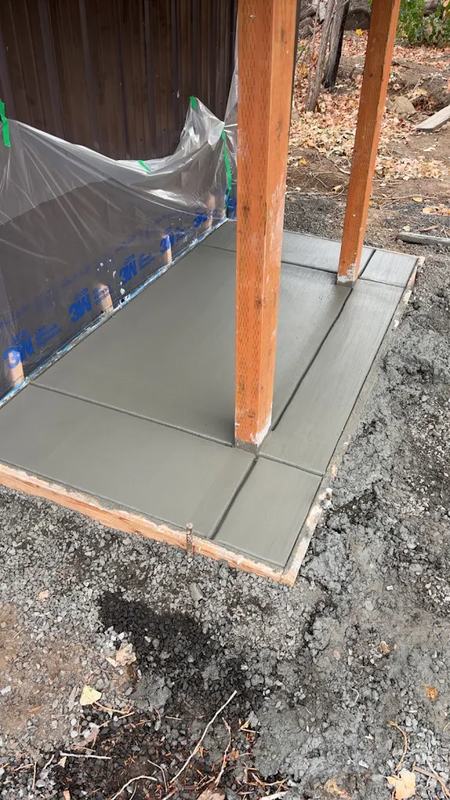 A new patio slab poured under a covered porch, forms still in place