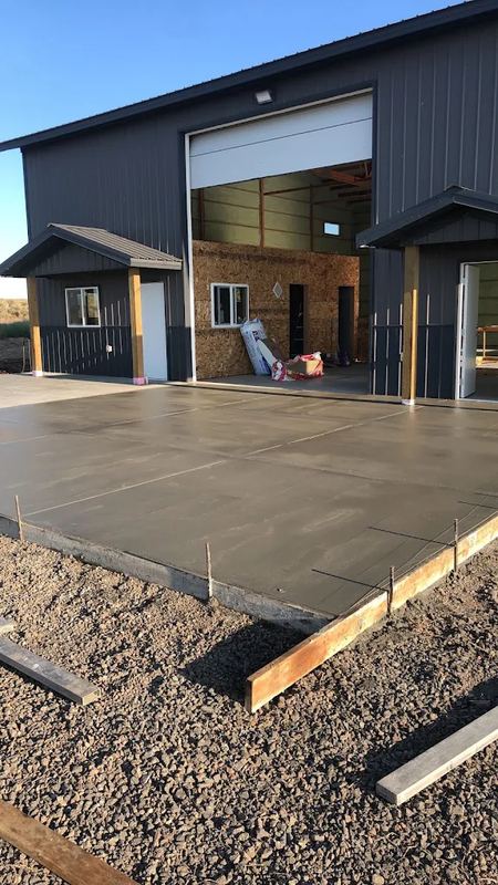 Finished concrete slab in front of a metal shop building with an open bay door