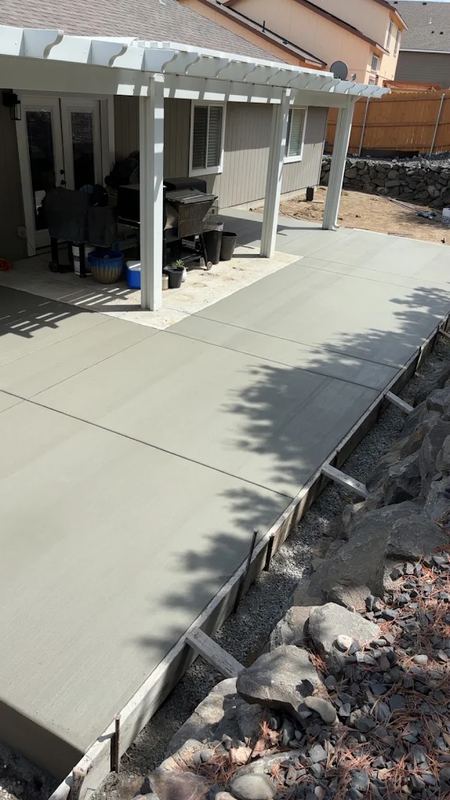 Finished concrete patio under a pergola with outdoor furniture