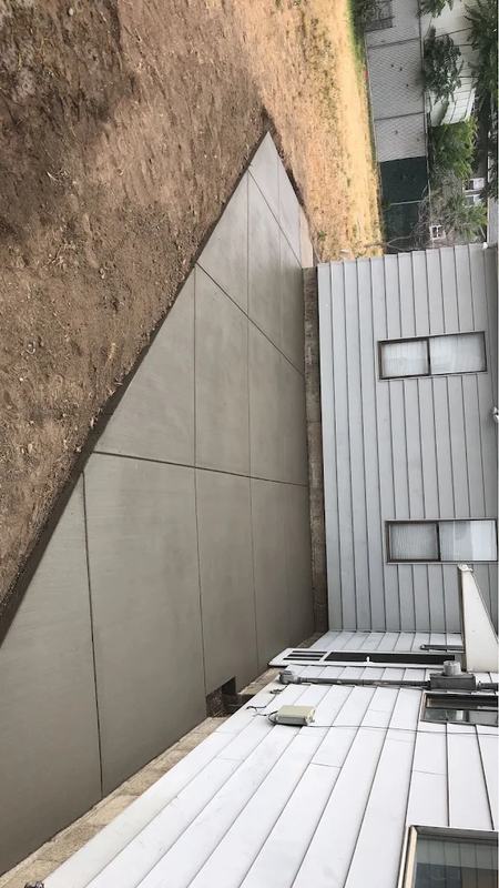 Diagonal concrete patio slab along the side of a home with white siding