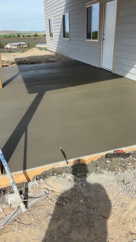 Newly poured concrete slab against a home, photographed in late-day shadow