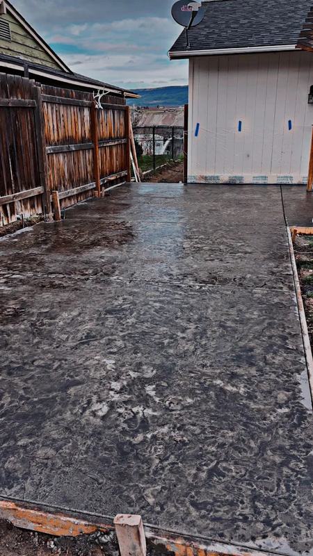 Finished concrete walkway running alongside a home next to a wood fence