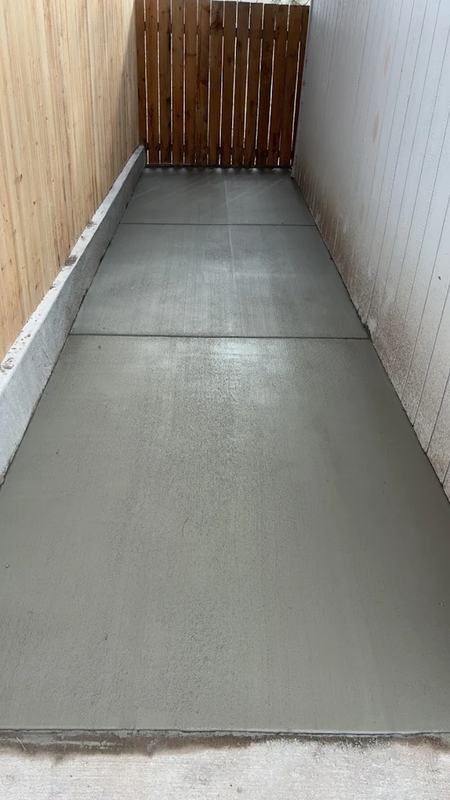 Narrow finished concrete walkway running along the side of a home