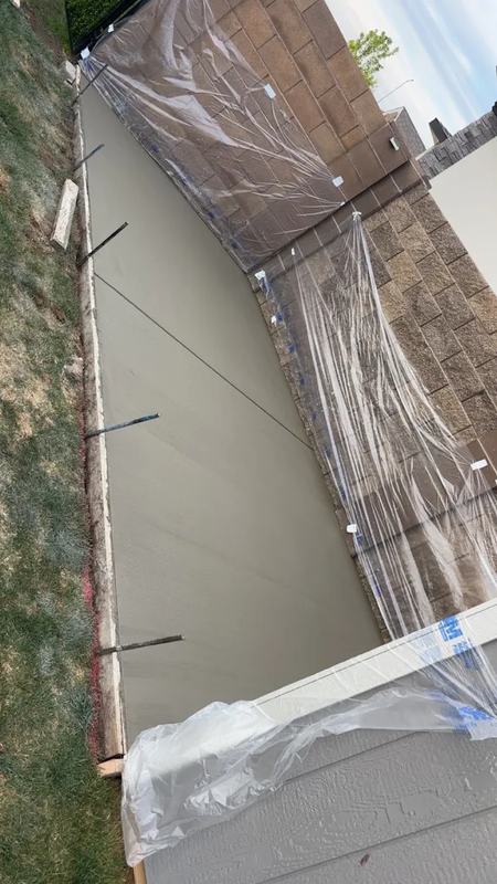 Overhead view of a formed concrete slab wrapped in plastic sheeting along its edges