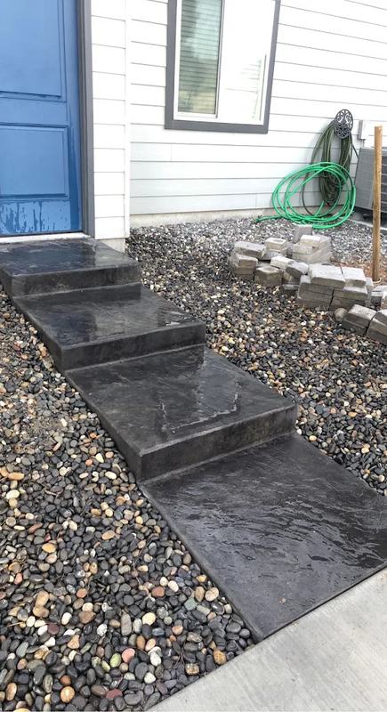 Stamped and colored concrete steps leading up to a home's blue entry door